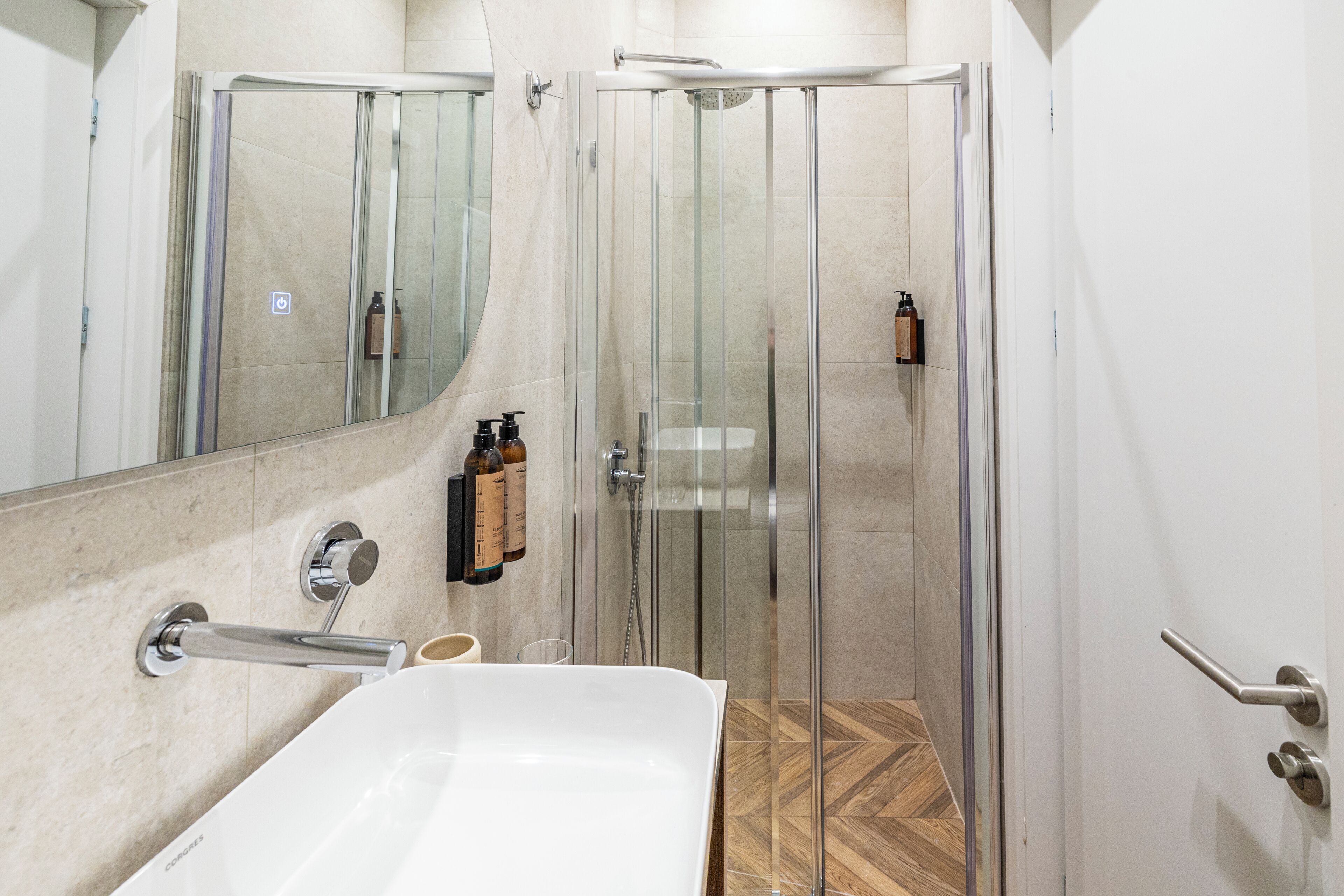 A modern bathroom with a glass-enclosed shower, a large white bathtub, and a mirror above the sink.
