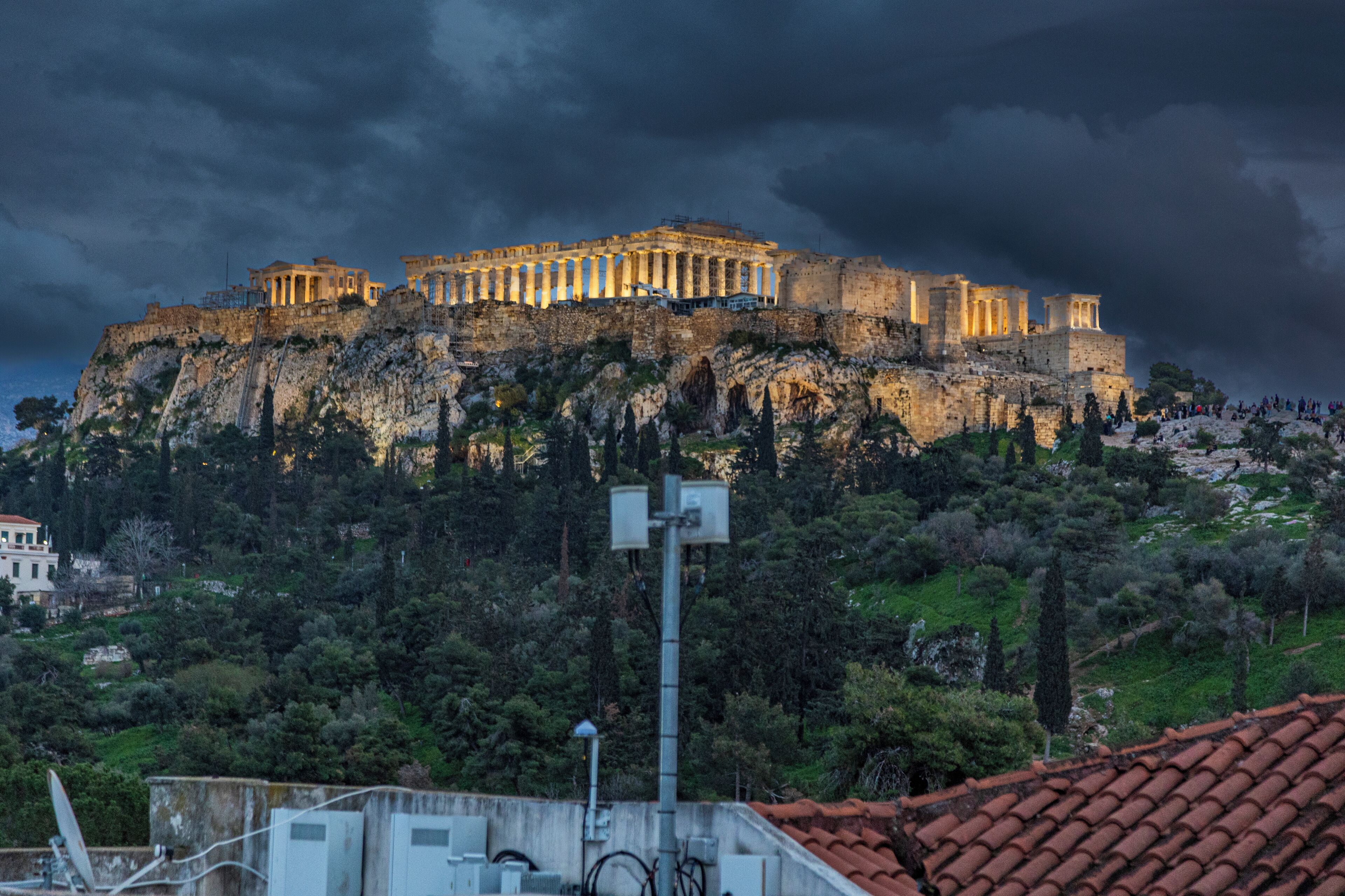 A historic building with classical architecture, situated on a hill with surrounding greenery.