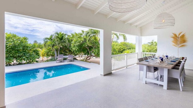 Un espace aménagé au bord de la piscine, comprenant une piscine, des sièges d’extérieur et une table à manger pour six personnes.