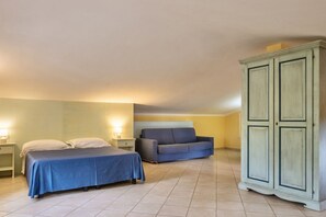 Un dormitorio con cama, sofá, armario y mesita de noche.