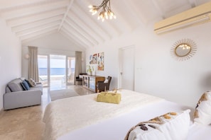 A spacious bedroom with a large bed, a sofa, and a desk area. - Seafront design villa with private pool (Sint Willibrordus)