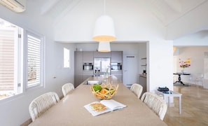 A modern kitchen with a central island, white cabinetry, and a hanging pendant light. - Seafront design villa with private pool (Sint Willibrordus)