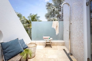 A small, private outdoor shower area with a tiled floor, a bench, and a towel rack. - Seafront design villa with private pool (Sint Willibrordus)