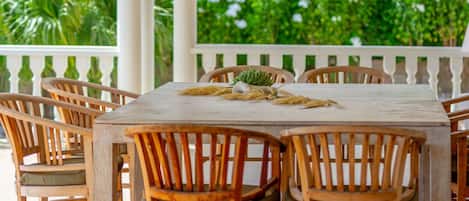 A wooden table with chairs, surrounded by lush greenery.