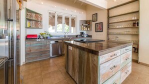 Uma cozinha moderna com ilha central, prateleiras embutidas e uma grande janela que proporciona luz natural.