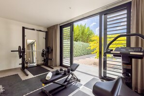 A gym with exercise equipment, a bench, and a treadmill. - Luxury villa with private beach and sea view (Sint Willibrordus)