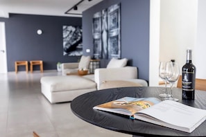 A modern living room with a round table, a sofa, and a wine bottle. - Luxury villa with private beach and sea view (Sint Willibrordus)