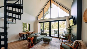 A spacious living area with a staircase, a dining table, a sofa, and a television.