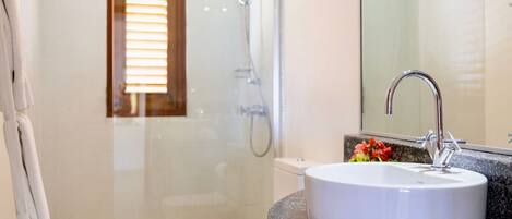 A bathroom with a white sink, a glass shower enclosure, and a toilet.