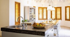 A kitchen with a granite countertop, stainless steel sink, and a bowl of fruit. - Oceanfront villa - infinity pool and private beach (Sint Willibrordus)
