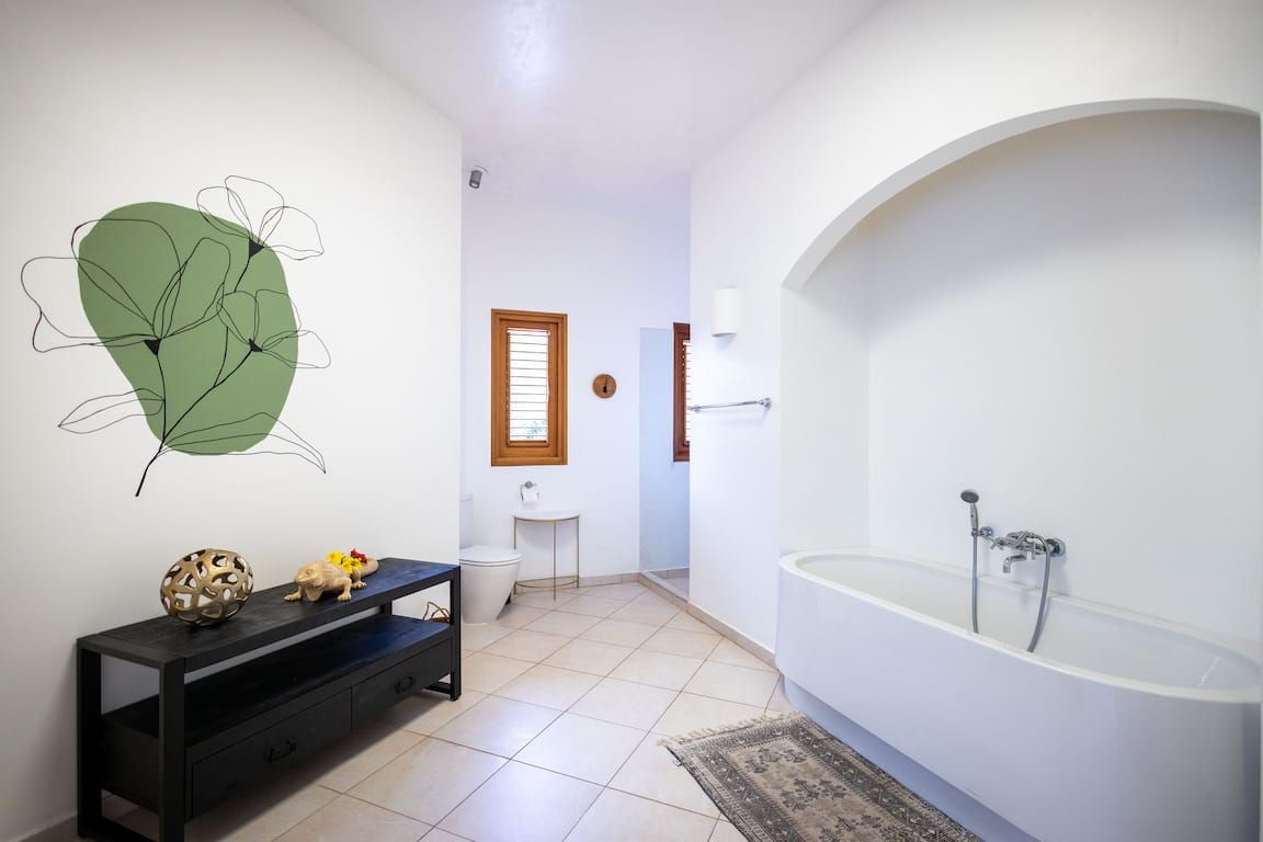 A bathroom with a bathtub, toilet, sink, and a decorative wall piece.