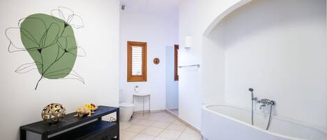 A bathroom with a bathtub, toilet, sink, and a decorative wall piece.