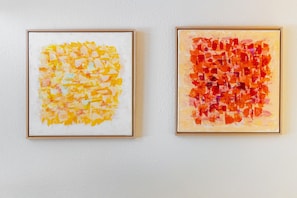 Duas pinturas abstratas emolduradas numa parede branca.