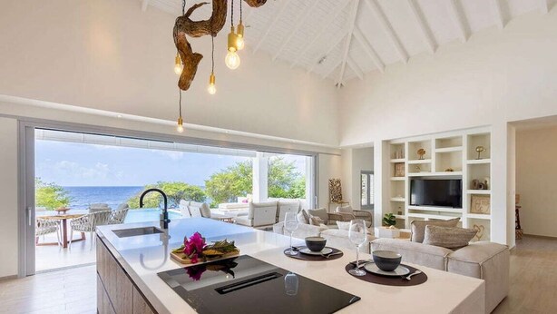 Cozinha moderna com uma ilha grande, forno embutido e vista para o oceano.