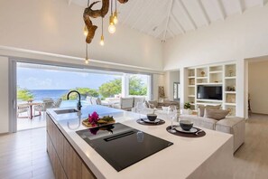 A modern kitchen with a large island, a built-in oven, and a view of the ocean. - Luxury seaside retreat with private beach (Sint Willibrordus)