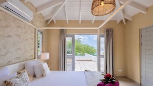 Quarto com cama, janela com cortinas, varanda e porta.