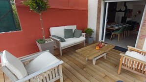 Una terraza de madera con un sofá blanco, una mesa de madera y una pequeña silla de madera.