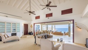 A spacious living area with a large sofa, a coffee table, and a view of the ocean. - Elegant seaside retreat with private beach - Coral Estate (Sint Willibrordus)