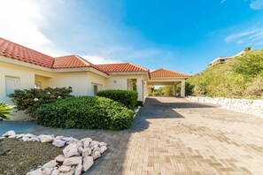 Propiedad residencial con camino de entrada pavimentado, acceso cubierto y jardín ajardinado.