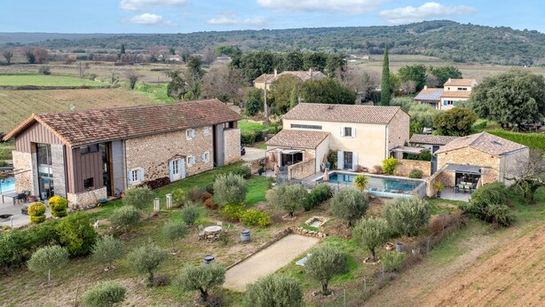 Una propiedad residencial con piscina, edificios de piedra y vistas al campo.