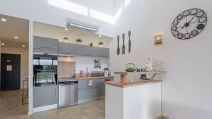 Una cocina moderna con armarios grises, horno empotrado y una isla central.