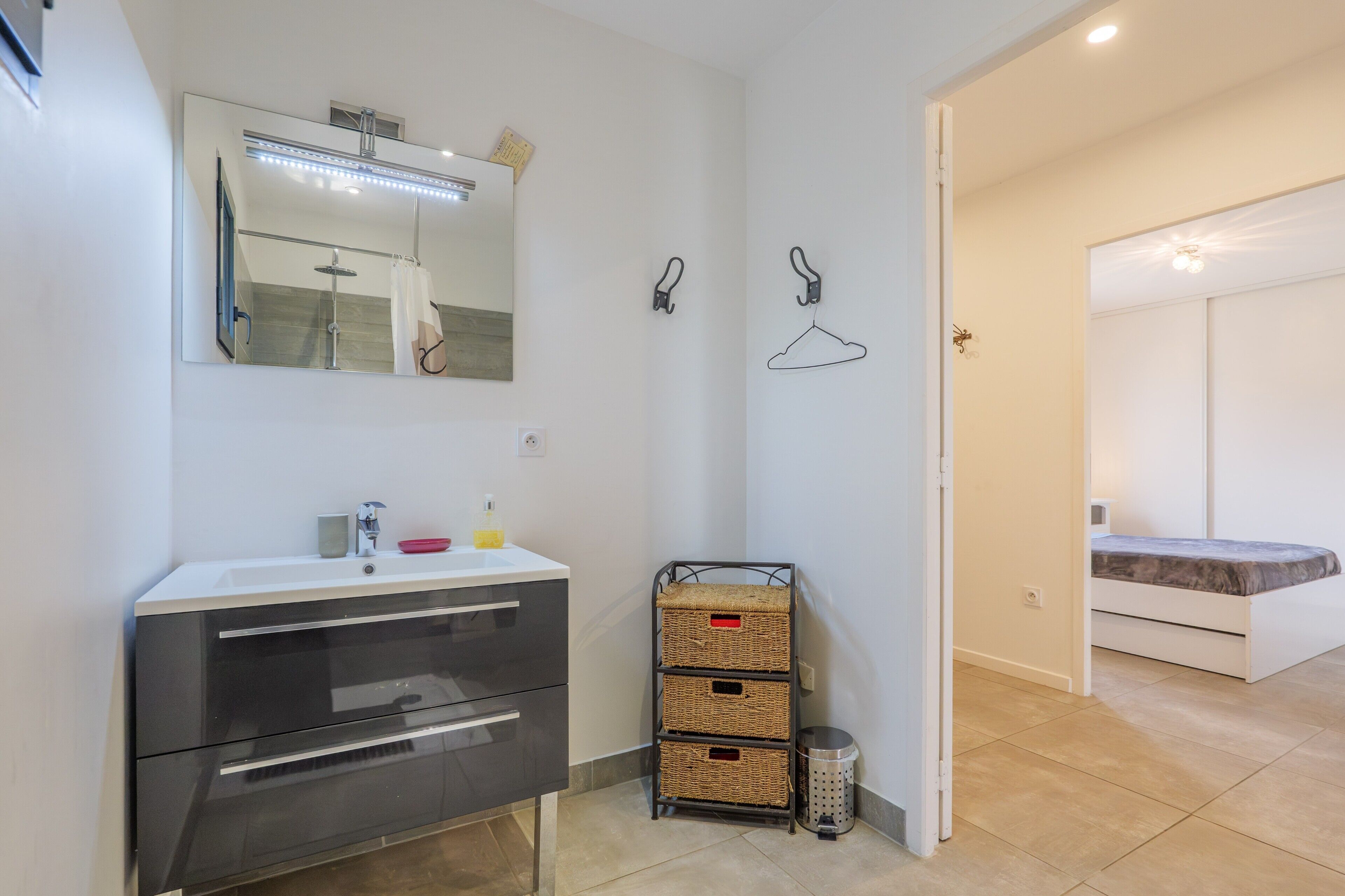 A modern bathroom with a mirror, sink, and storage baskets.