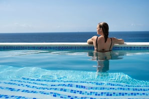 A person relaxing in a swimming pool with a view of the ocean. - Villa Caribbean Breeze 218 (Sint Willibrordus)