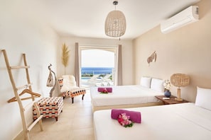 A hotel room with two beds, a hanging light fixture, a view of the sea, and a wooden chair. - Villa Caribbean Breeze 218 (Sint Willibrordus)