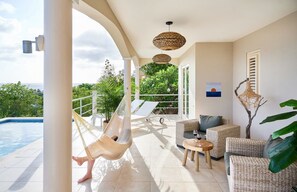 Ein geräumiger Balkon mit Pool, Korbmöbeln und einer Hängematte.