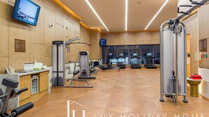 Ett gym med träningsutrustning, en tv och en receptionsdisk.