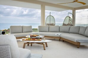 A modern living room with a curved sectional sofa, a round coffee table, and a view of the ocean. - Spacious luxury villa with panoramic sea views (Sint Willibrordus)