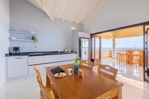 Eine moderne Küche mit weißen Schränken, einer schwarzen Arbeitsplatte und einem Essbereich mit einem Holztisch und Stühlen.