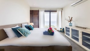 A hotel room with a large bed, a desk, and a view of the outdoors. - Design villa with sea views and infinity pool (Sint Willibrordus)