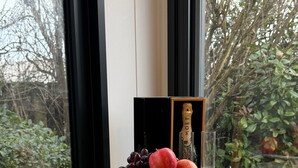 A wooden table with a fruit and champagne display in front of a window. - Old Mill Tiny Homes (Yarm)