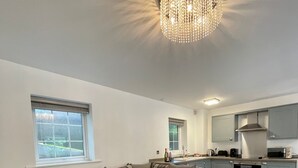 A modern living room with a sectional sofa, a wooden coffee table, and a chandelier. - Old Mill Tiny Homes (Yarm)