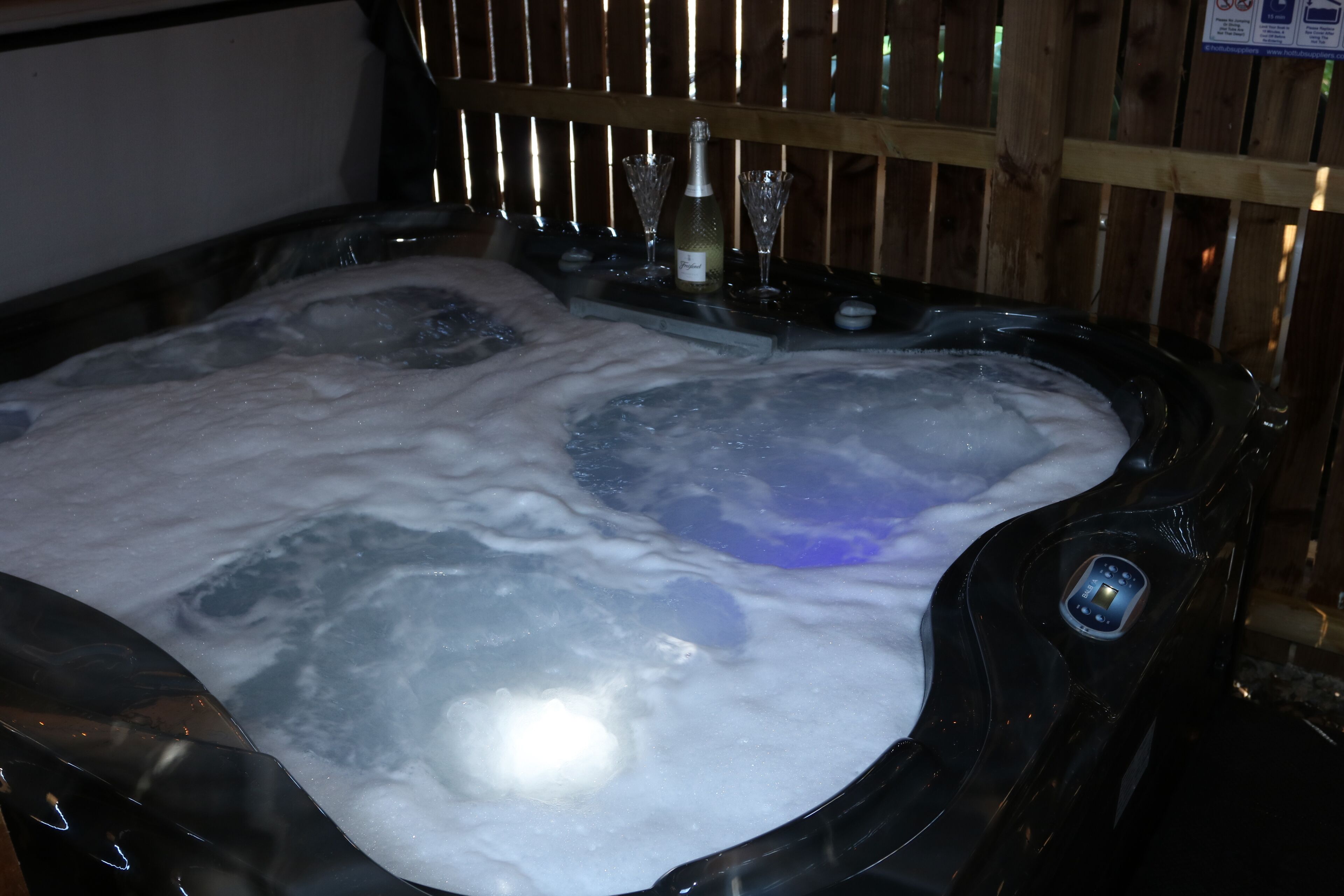 Un jacuzzi con burbujas, una botella y dos vasos.