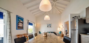 A modern kitchen with a large island, stainless steel appliances, and pendant lighting. - Panoramic sea-view villa with private pool (Sint Willibrordus)