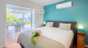 A bedroom with a bed, a fan, and a view of the outdoors. - Spacious villa with pool and ocean views (Sint Willibrordus)
