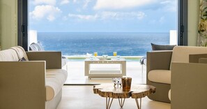 A living room with a view of the ocean, a white coffee table, and two sofas. - Designer sea-view villa with private pool (Sint Willibrordus)