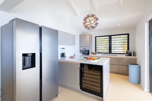A modern kitchen with a built-in oven, a water dispenser, and a wine cooler. - Designer sea-view villa with private pool (Sint Willibrordus)