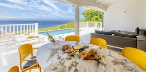 A dining area with a view of the ocean, a pool, and a sofa. - Designer sea-view villa with private pool - Coral Estate (Sint Willibrordus)