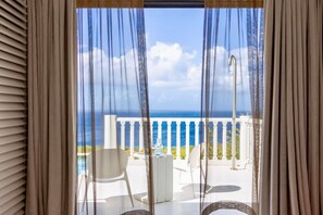 Ein Balkon mit Meerblick, weißen Stühlen und einem kleinen Tisch.
