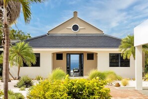 A modern house with a triangular roof, a circular window, and a view of the ocean. - Designer sea-view villa with private pool - Coral Estate (Sint Willibrordus)