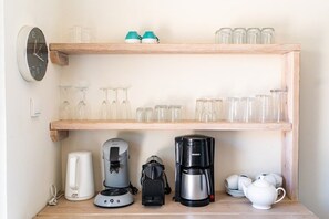 Ein Küchenbereich mit einer Kaffeemaschine, einem Wasserkocher und einem Teekessel auf der Arbeitsfläche.