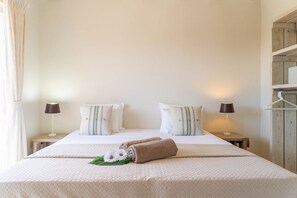 A hotel room with a large bed, two bedside tables, and a wooden wardrobe. - Tranquil tropical villa with private pool (Sint Willibrordus)