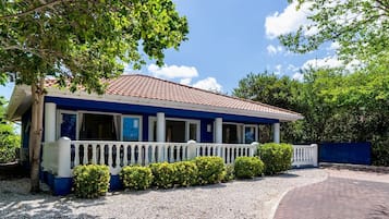 A two-story building with a blue and white exterior, a covered porch, and a gravel driveway.