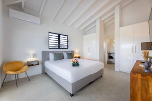 A modern hotel room with a large bed, a chair, bedside tables, and a wardrobe. - Modern villa with infinity pool and sea views (Sint Willibrordus)