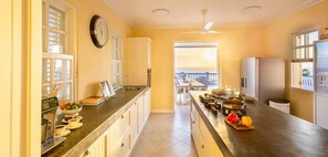 A kitchen with a long countertop, a coffee machine, and a view of the balcony. - Serene luxury retreat with pool and sea views - Coral Estate (Sint Willibrordus)