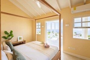 A bedroom with a bed, a bedside table with a plant, and a view of the sea through a large window. - Serene luxury retreat with pool and sea views - Coral Estate (Sint Willibrordus)
