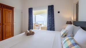 A hotel room with a bed, a wardrobe, a view of the sea, and a balcony with outdoor furniture. - Sea-view villa with private magnesium pool - Coral Estate (Sint Willibrordus)